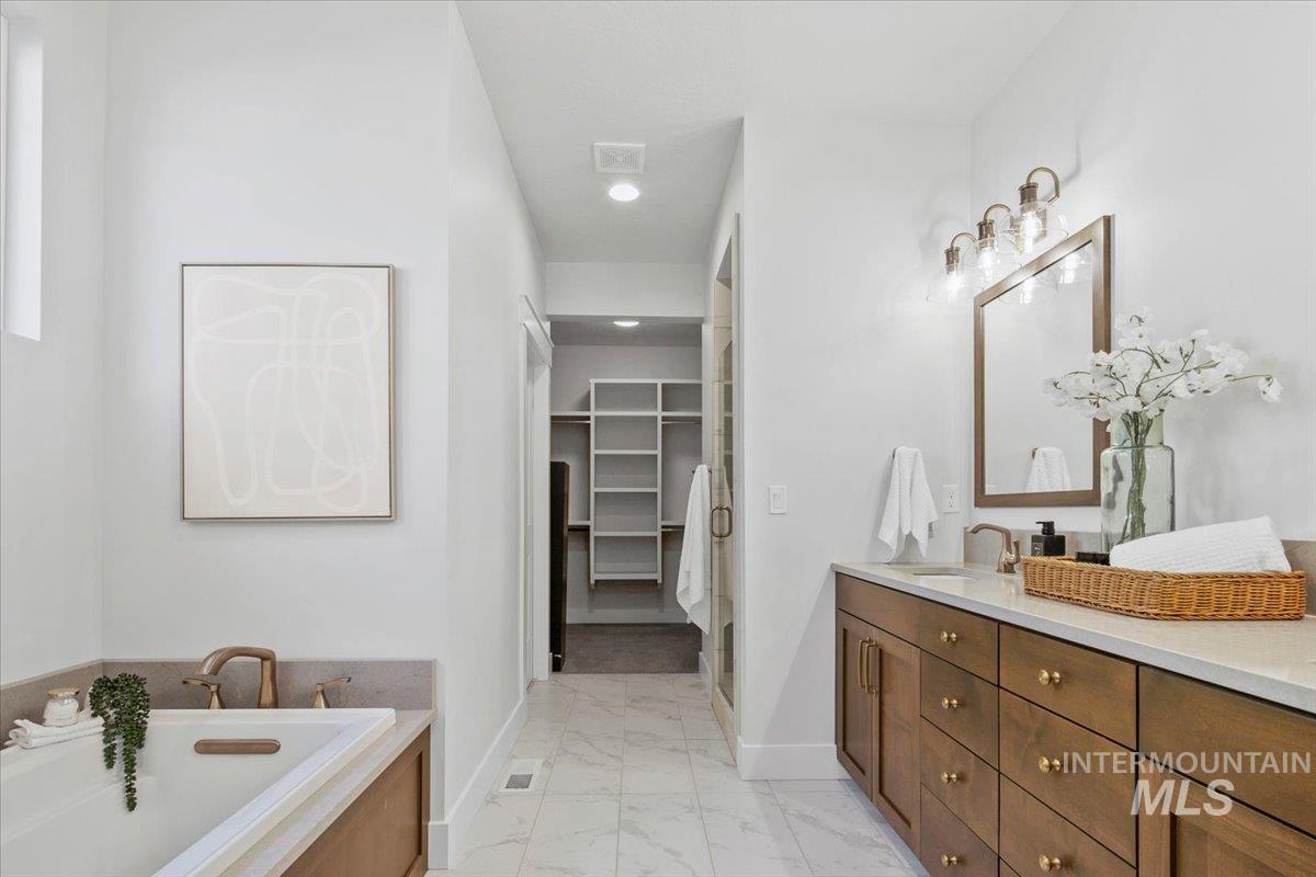 Full bathroom with vanity, a spacious closet, light marble finish flooring, a garden tub, and recessed lighting