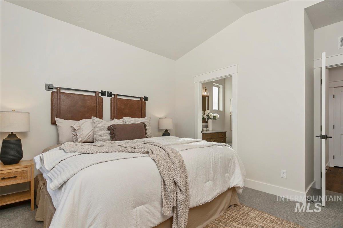 Bedroom featuring carpet floors, lofted ceiling, and connected bathroom