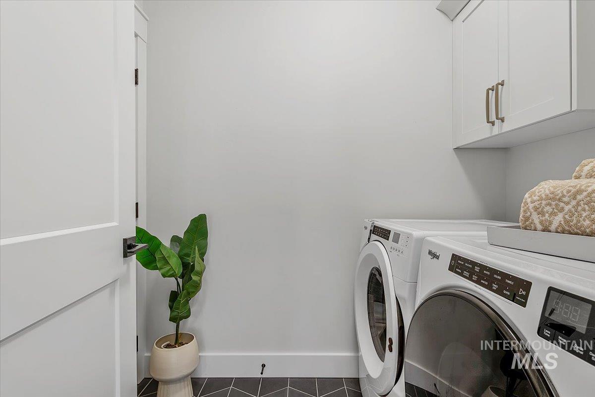 Laundry room with tile patterned floors, cabinet space, and separate washer and dryer