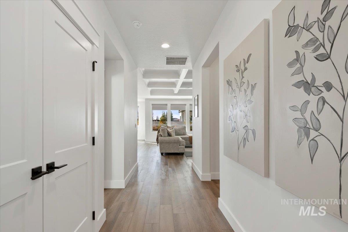 Hallway with coffered ceiling, beamed ceiling, light wood-type flooring, and recessed lighting