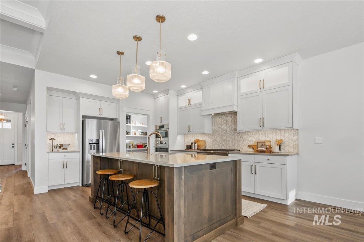 Kitchen with white cabinets, hanging light fixtures, stainless steel appliances, and recessed lighting
