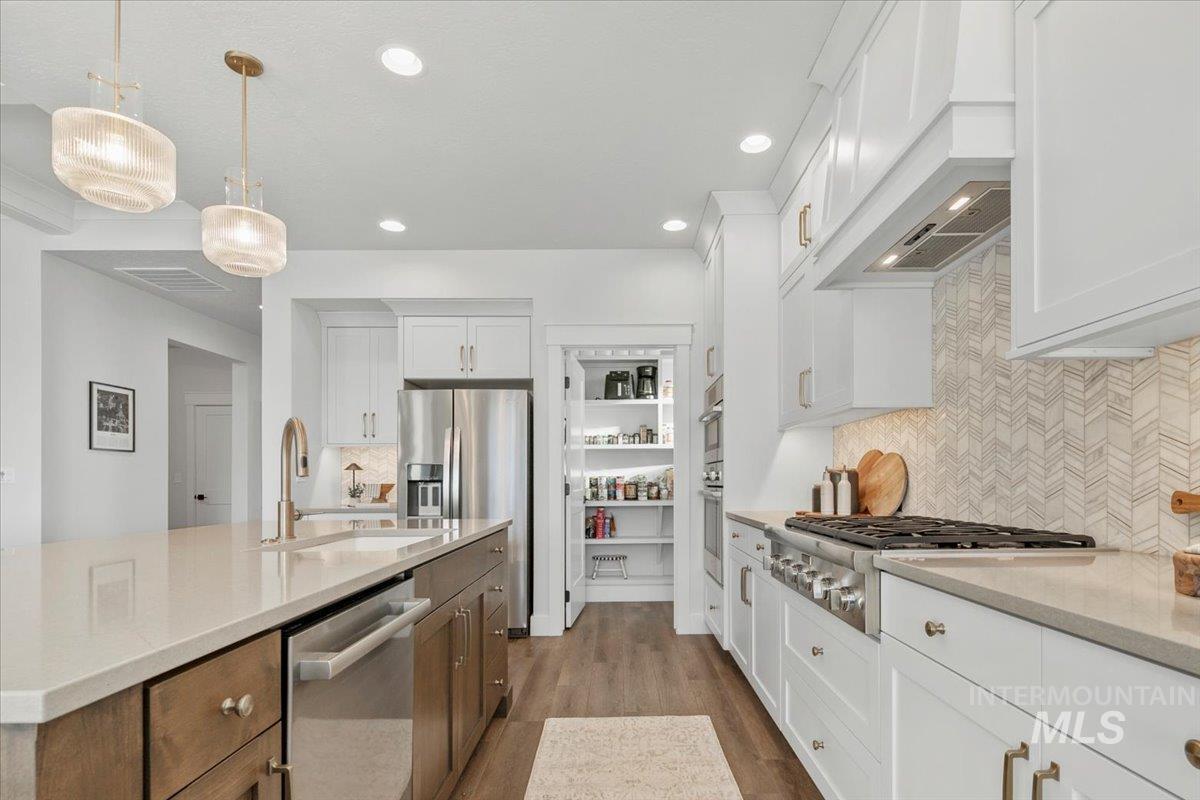 Kitchen with decorative backsplash, white cabinetry, appliances with stainless steel finishes, dark wood finished floors, and recessed lighting