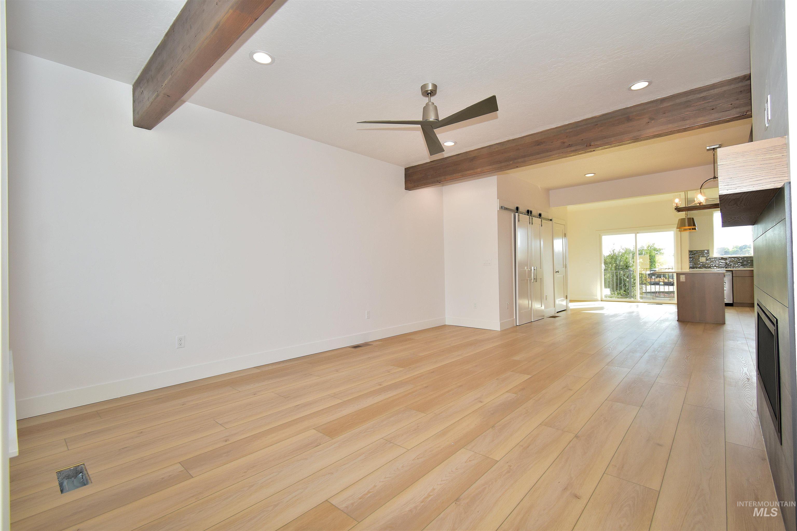Unfurnished room featuring beamed ceiling, a barn door, a ceiling fan, light wood-style flooring, and recessed lighting