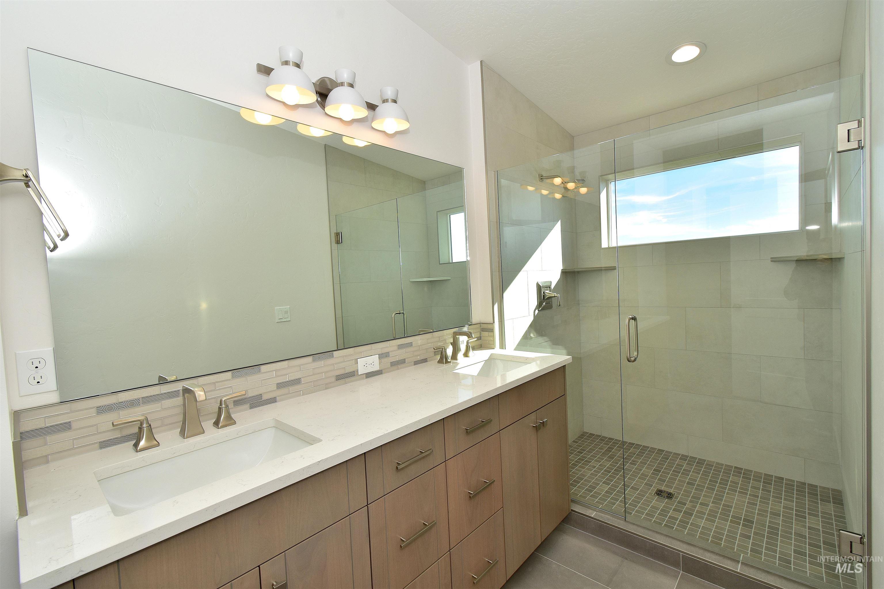 Full bath featuring backsplash, double vanity, a shower stall, light tile patterned flooring, and recessed lighting