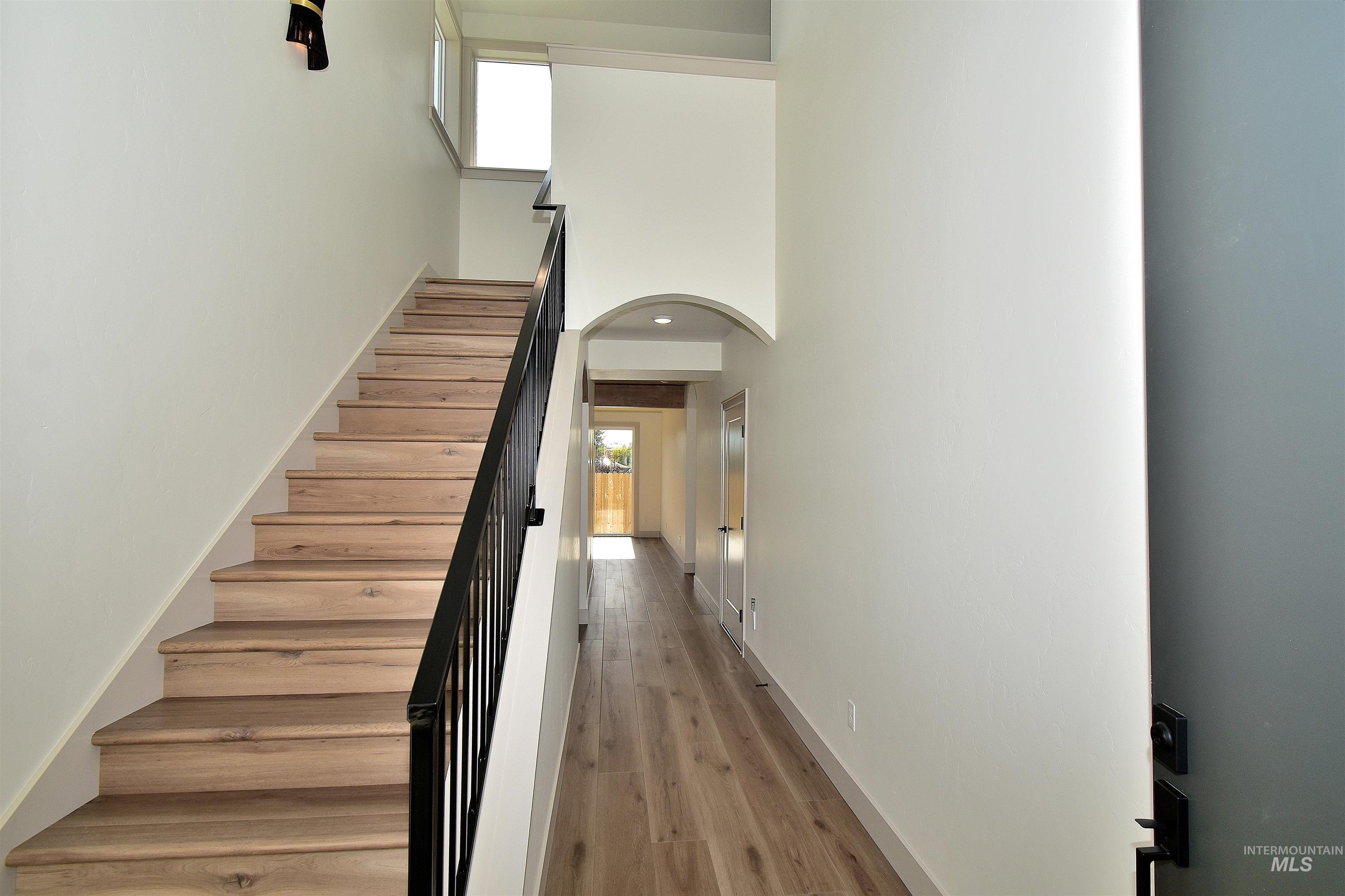Stairs featuring arched walkways, a high ceiling, and wood finished floors
