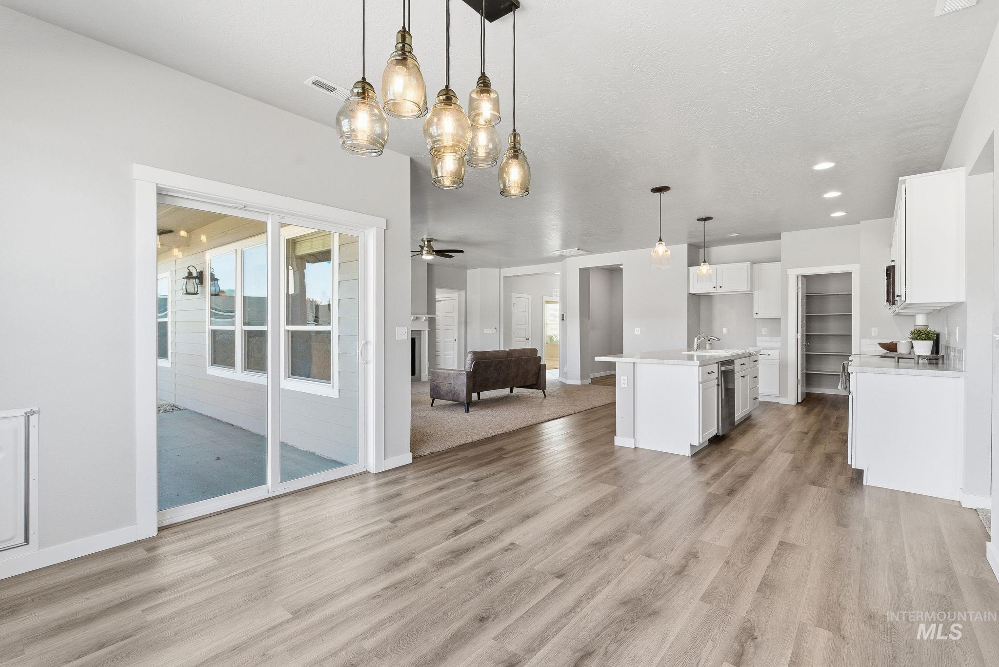 Unfurnished living room with light wood-style flooring, a chandelier, ceiling fan, and recessed lighting
