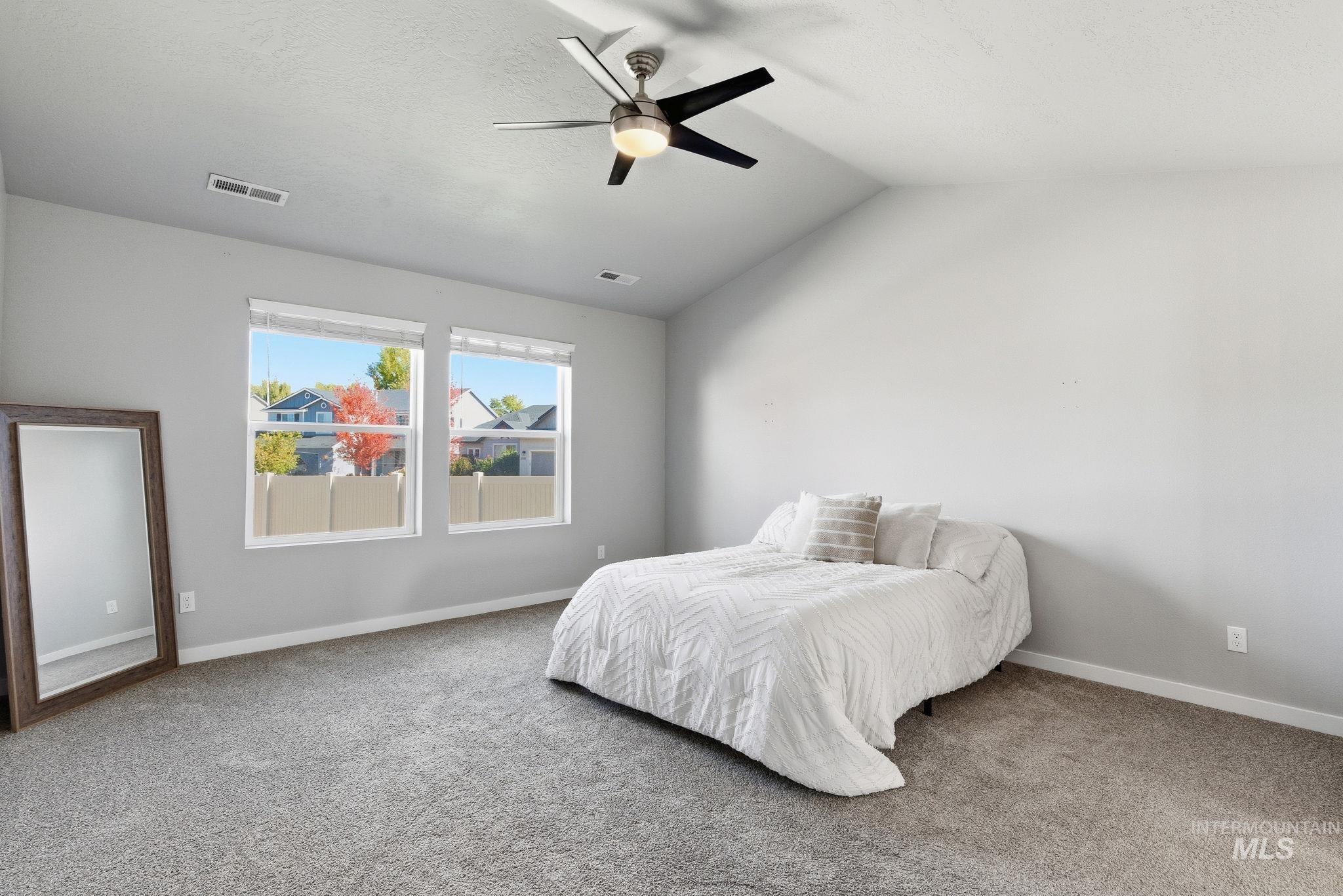 Bedroom with lofted ceiling, carpet, and a ceiling fan