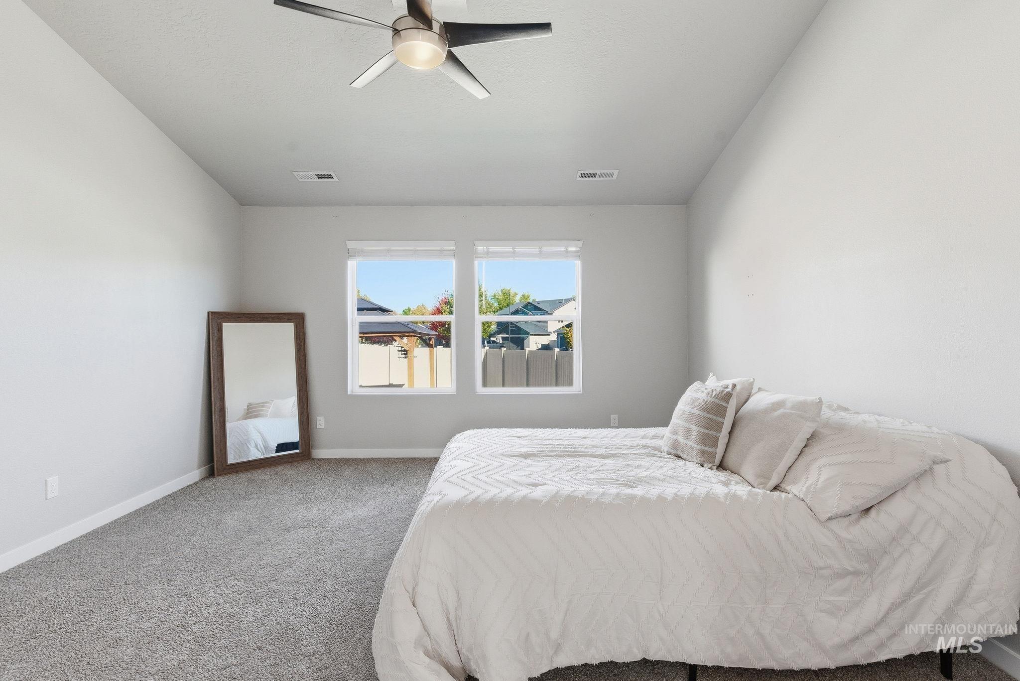 Carpeted bedroom with a ceiling fan and baseboards