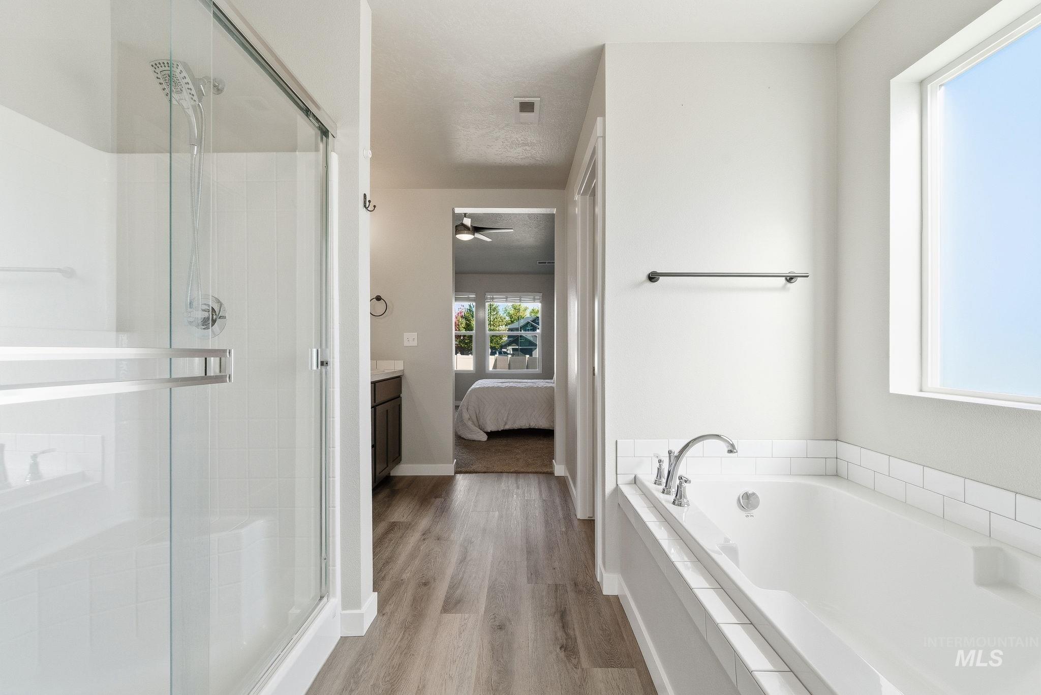 Full bathroom with connected bathroom, light wood-style flooring, a bath, a stall shower, and vanity