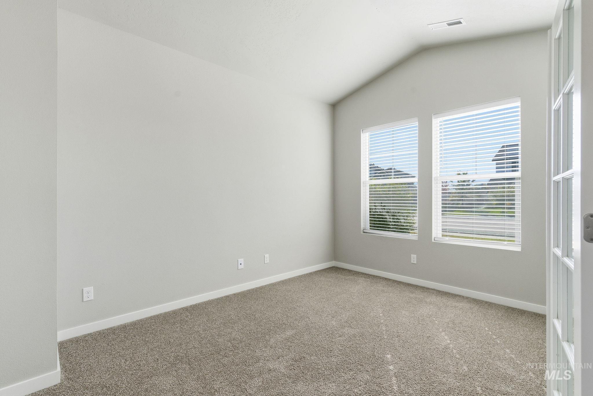 Spare room with vaulted ceiling and light colored carpet