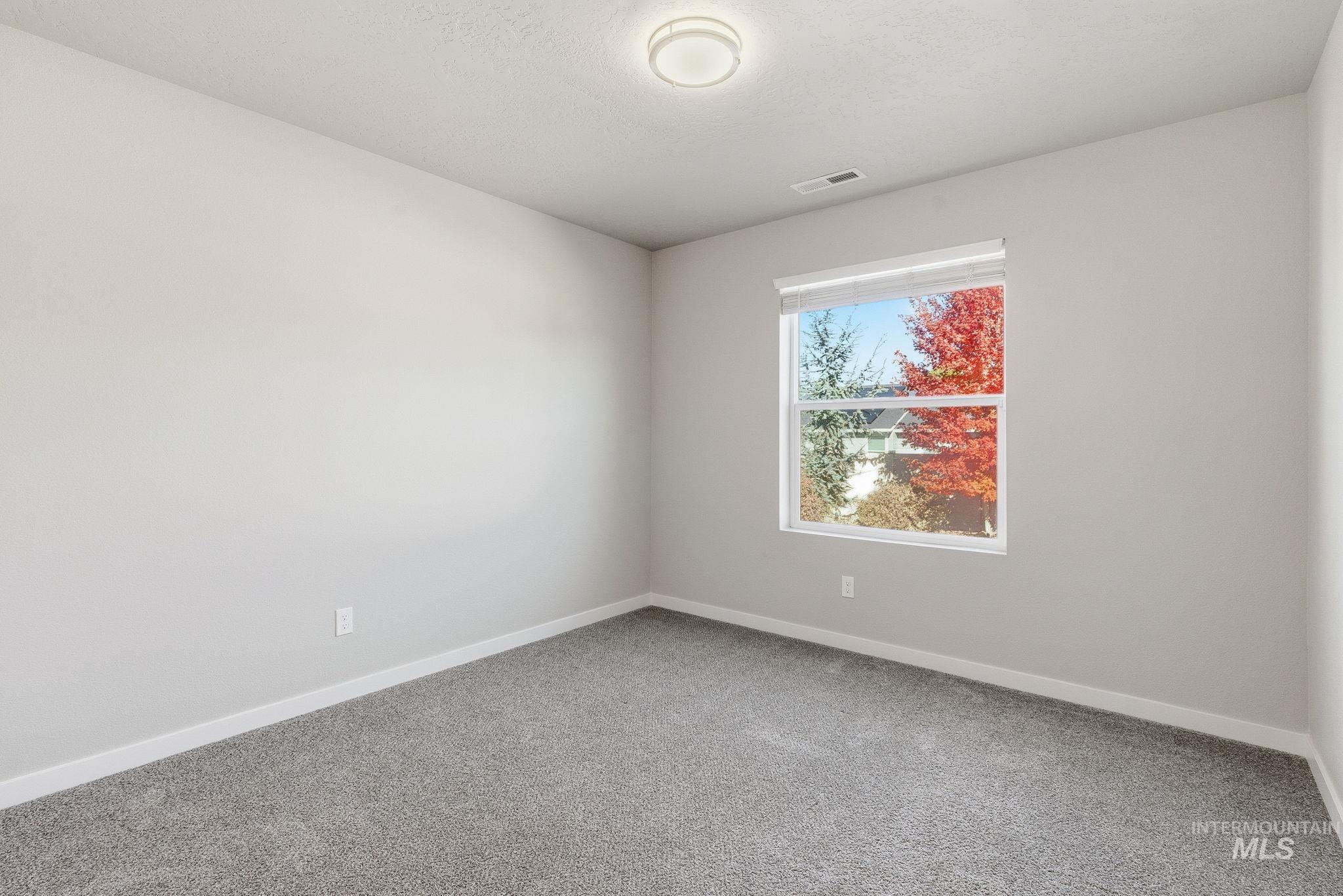 Spare room featuring light carpet and a textured ceiling