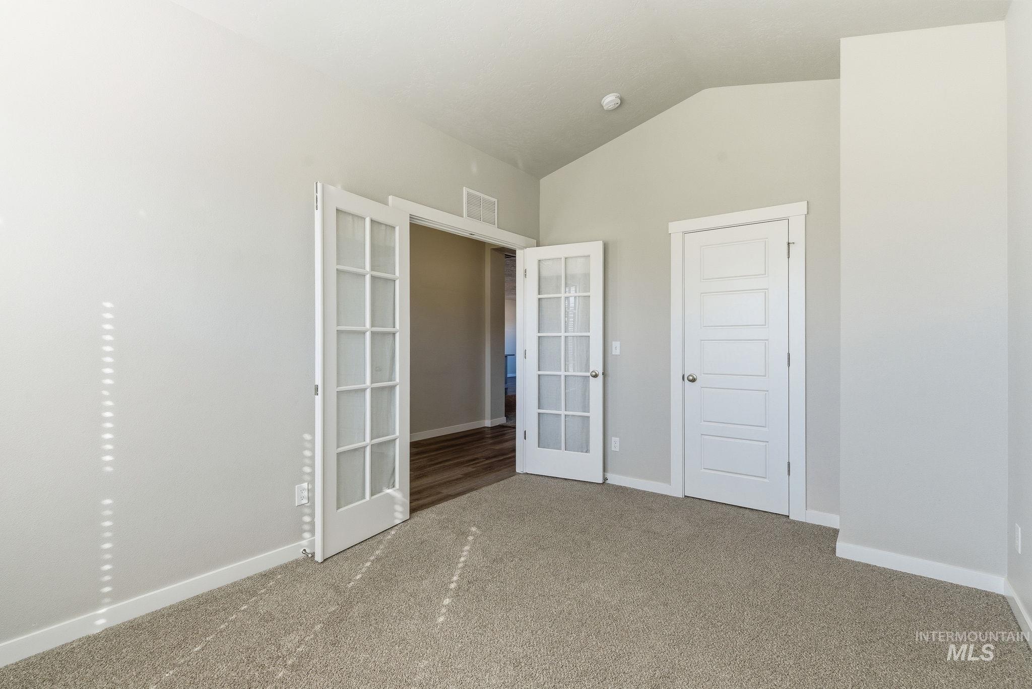 Unfurnished room with french doors, vaulted ceiling, and carpet