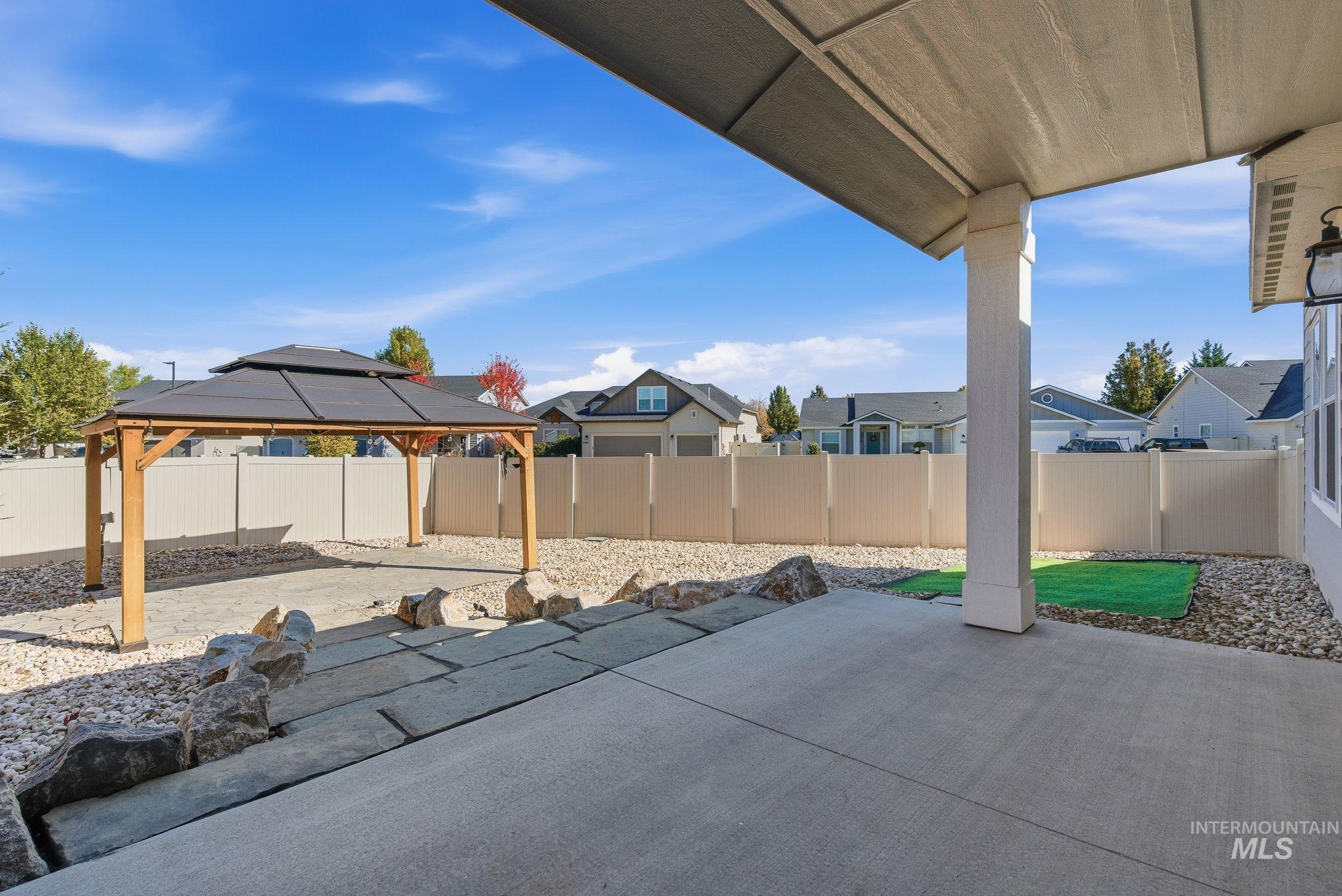 Fenced backyard featuring a patio area, a residential view, and a gazebo