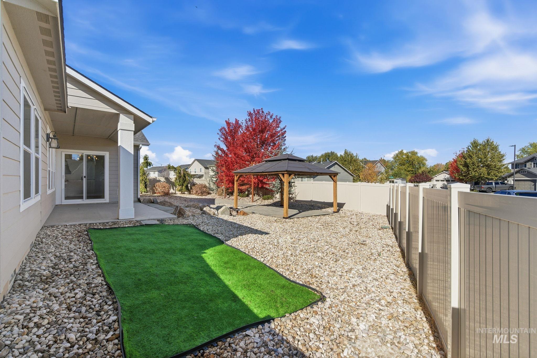 Fenced backyard with a patio, a residential view, and a gazebo