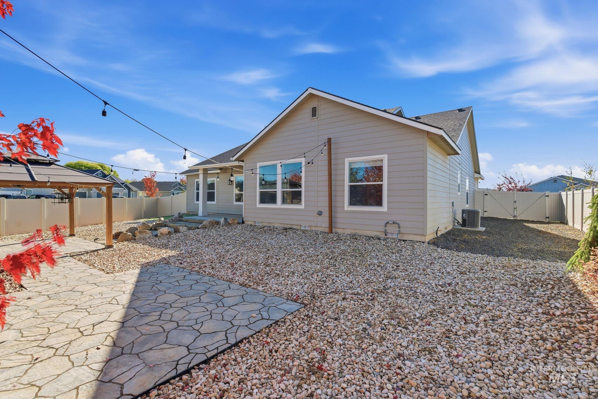 Rear view of house featuring a patio area, a fenced backyard, a gazebo, a shingled roof, and a gate