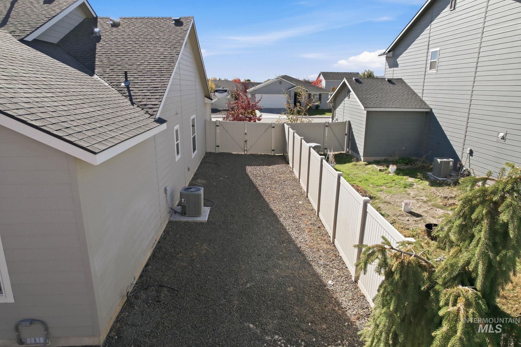 View of side of property featuring roof with shingles, a fenced backyard, and a residential view