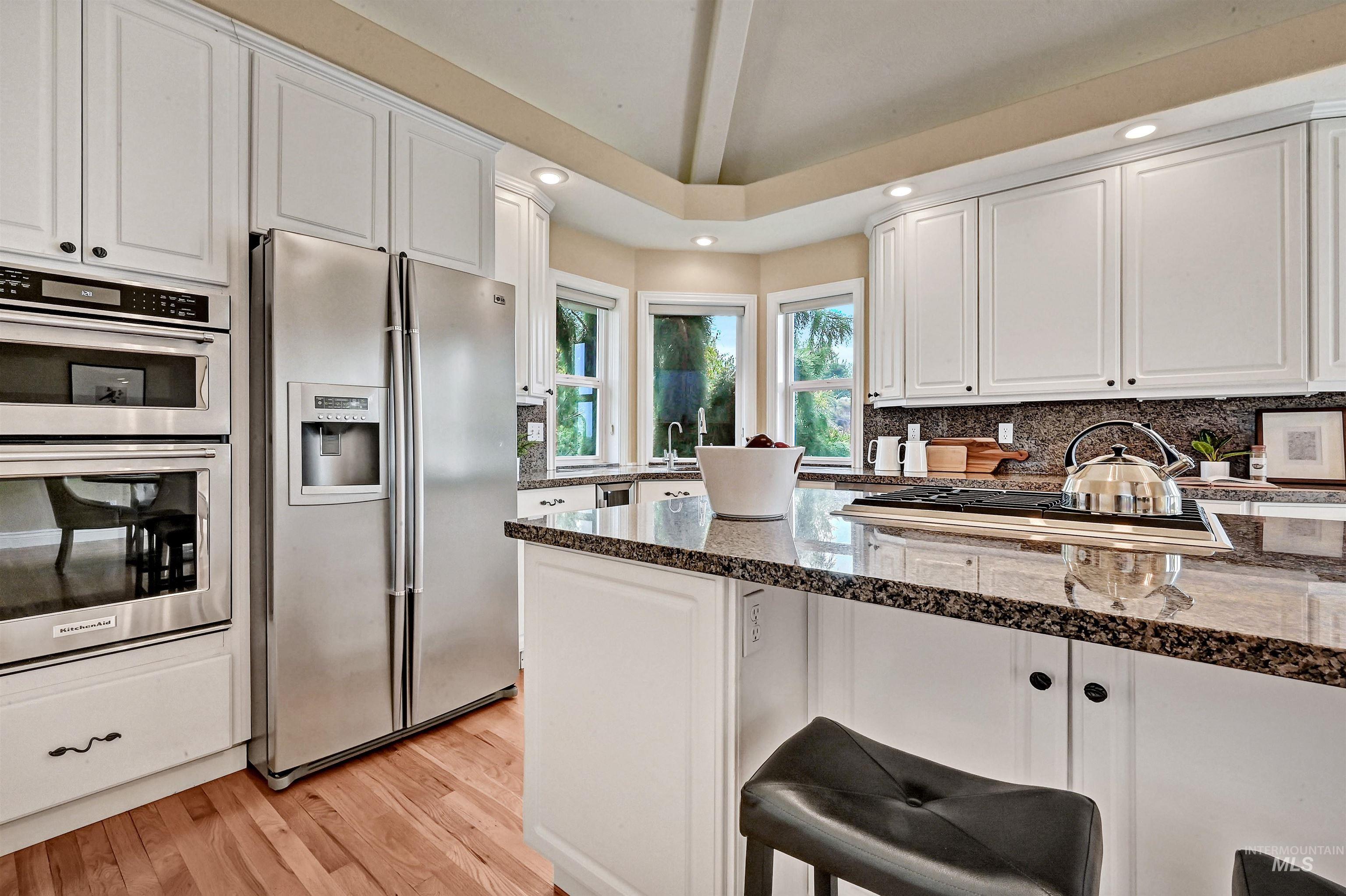 Kitchen with recessed lighting, white cabinetry, stainless steel appliances, light wood-style flooring, and tasteful backsplash