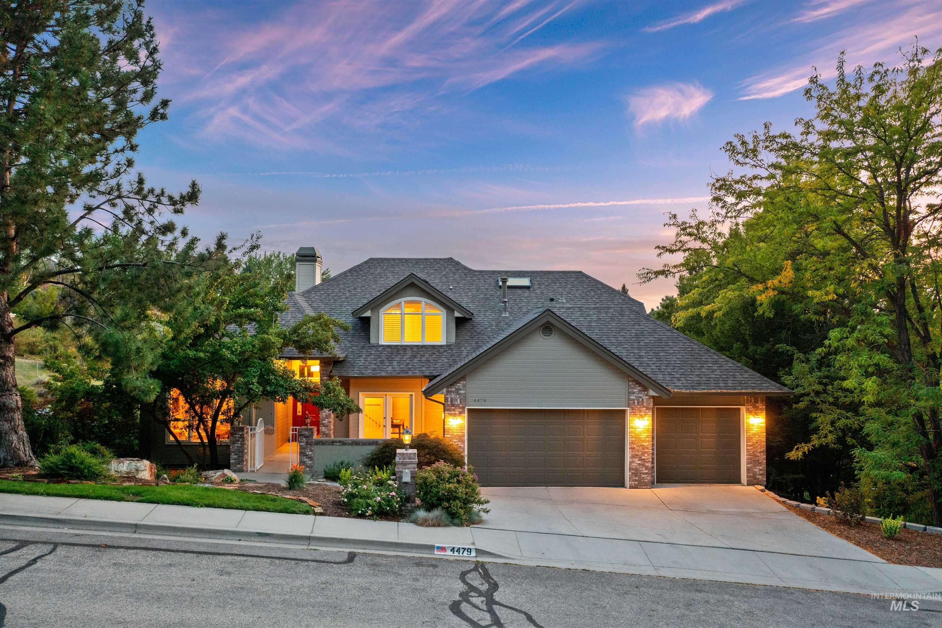 View of front of home with driveway, an attached garage, a chimney, stone siding, and a shingled roof