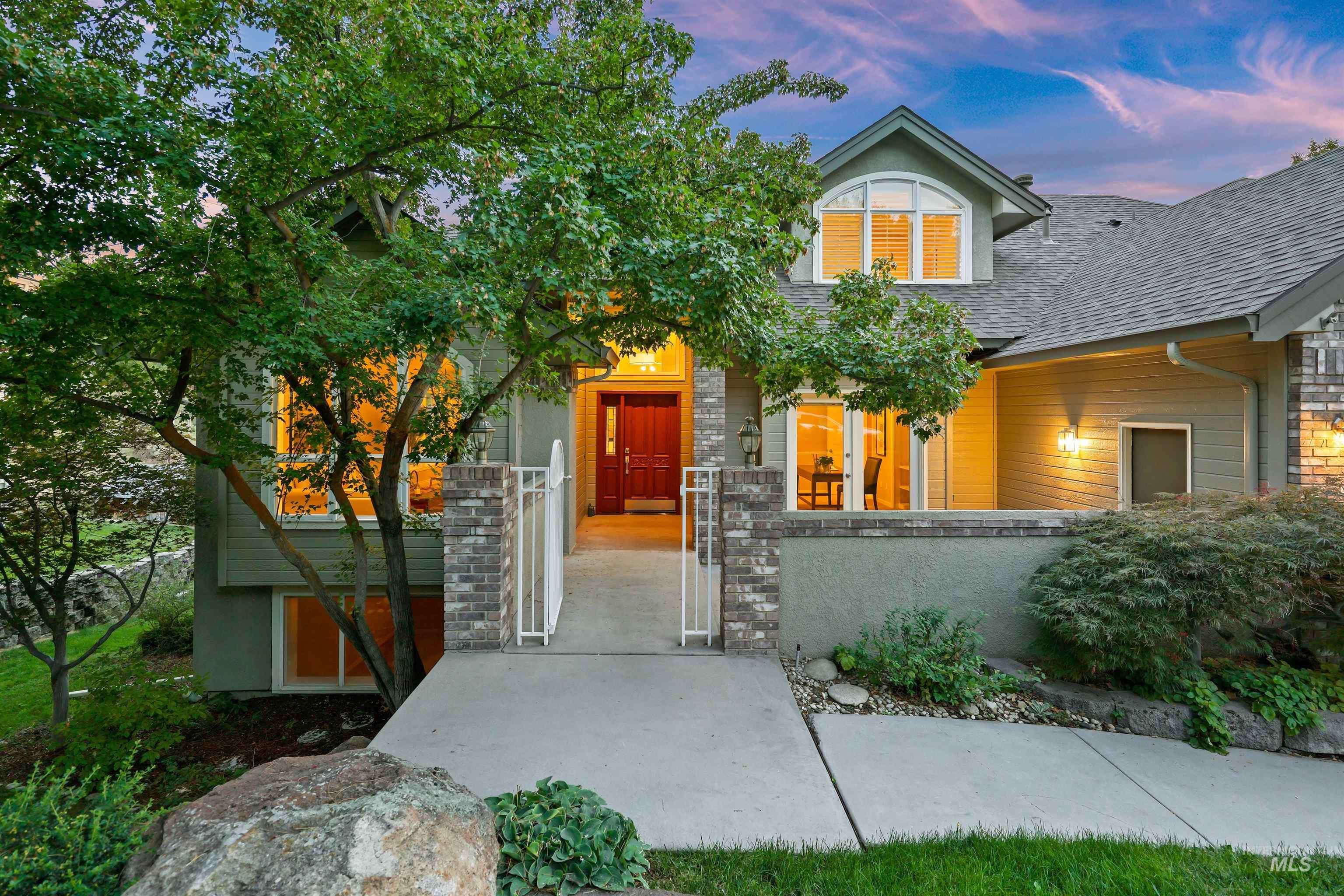Exterior entry at dusk featuring roof with shingles and a gate