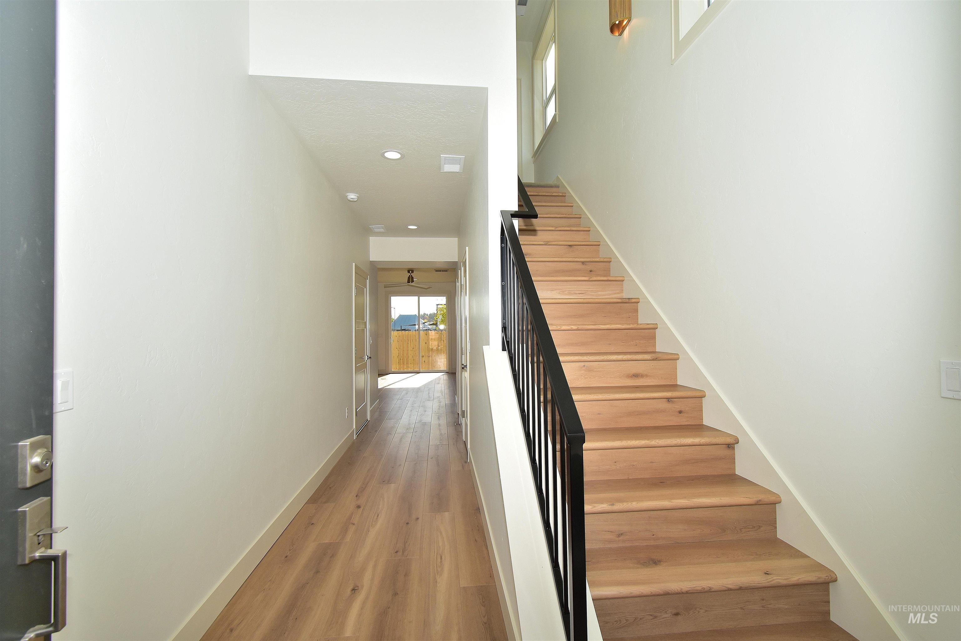 Staircase with wood finished floors and recessed lighting
