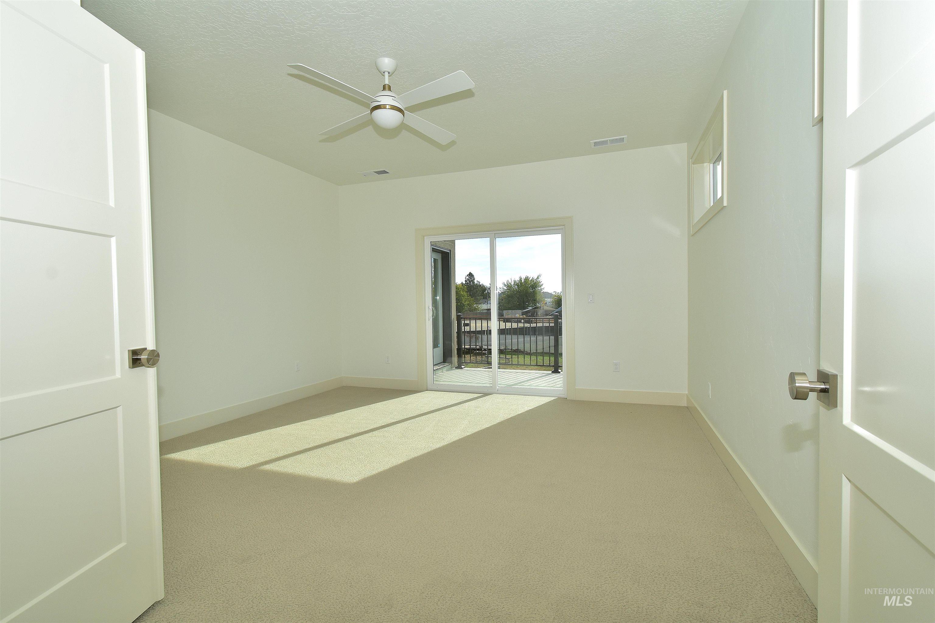 Empty room featuring carpet, ceiling fan, and a textured ceiling