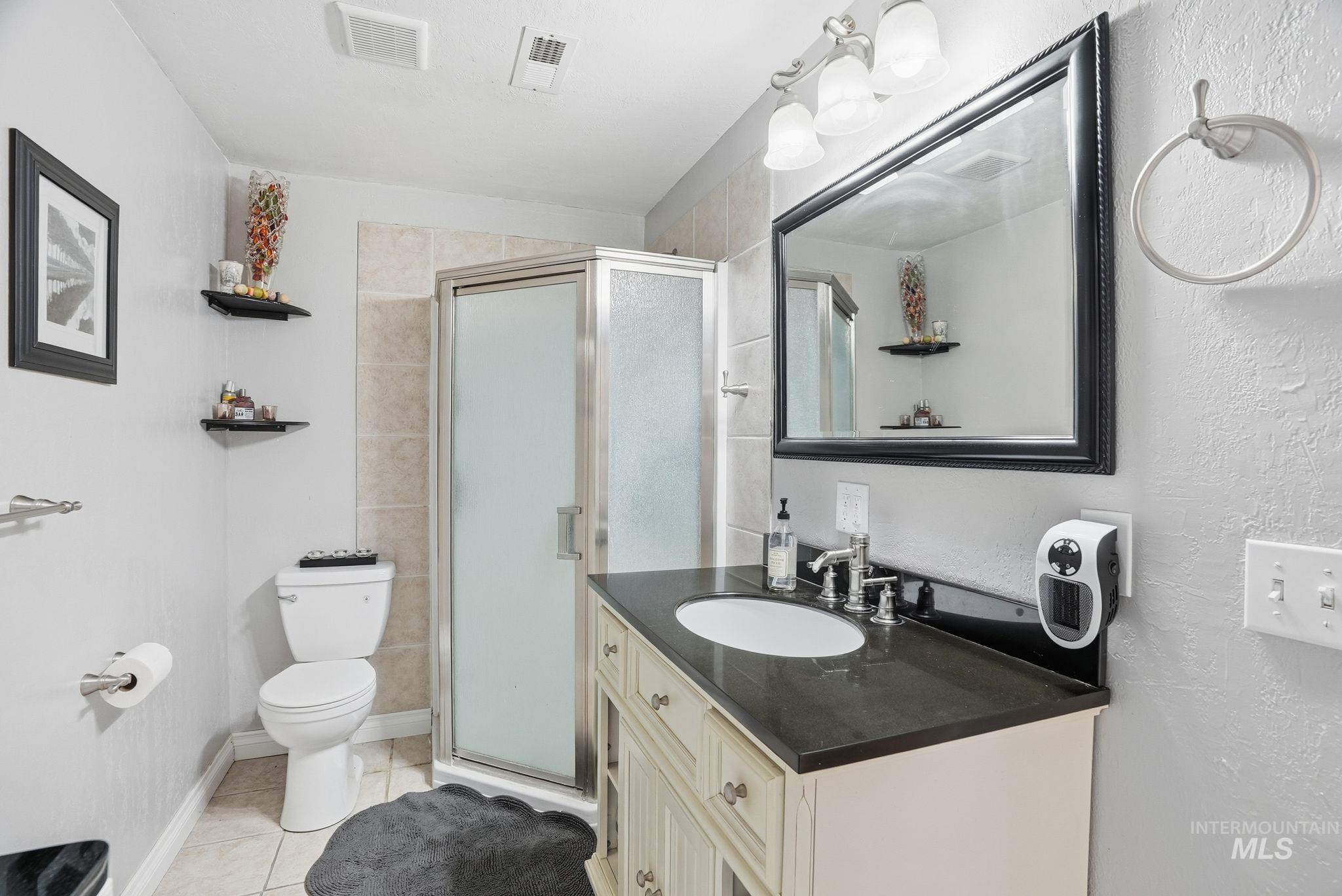 Full bathroom with light tile patterned floors, vanity, a shower stall, and a textured wall