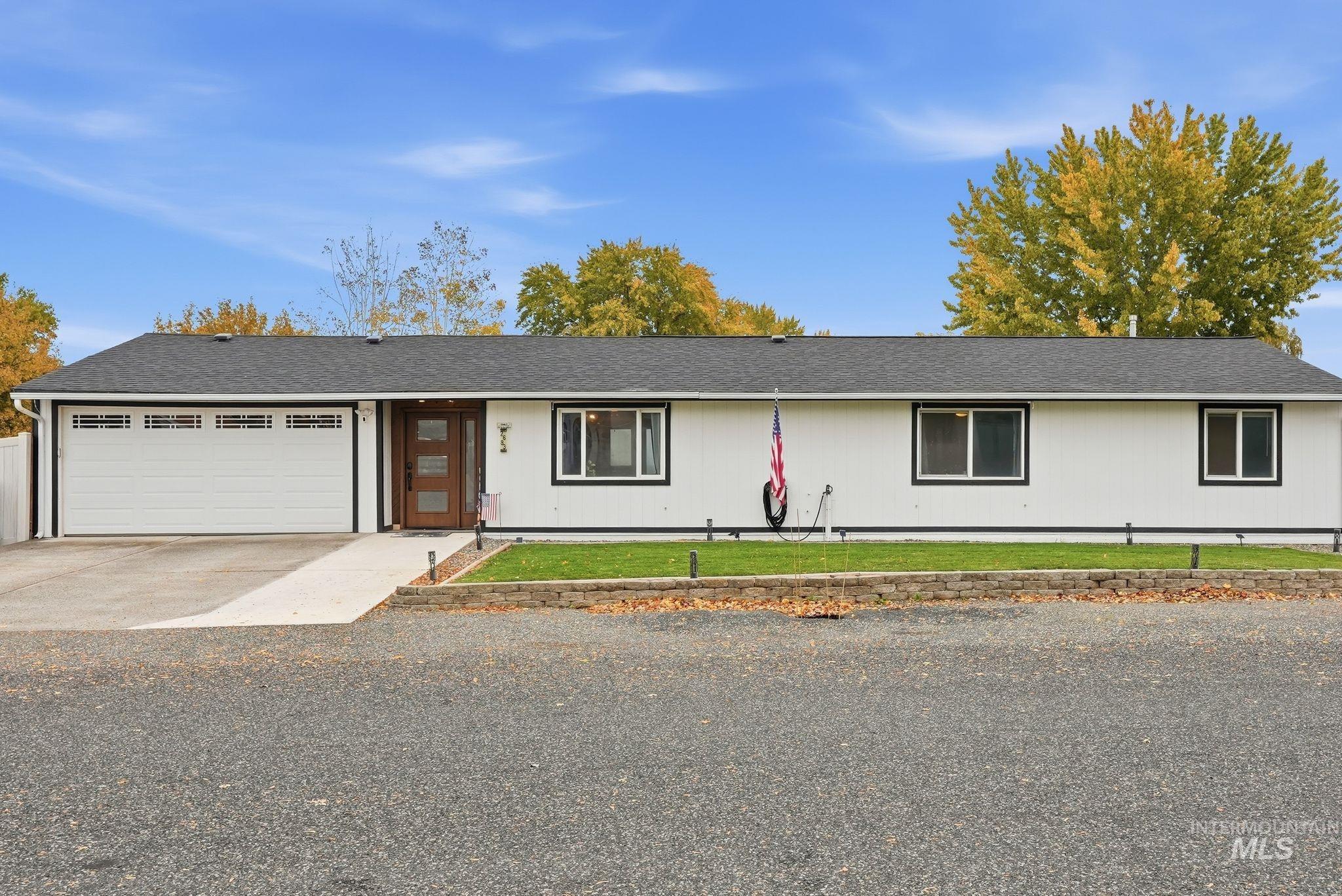 Single story home featuring roof with shingles, concrete driveway, an attached garage, and a front yard