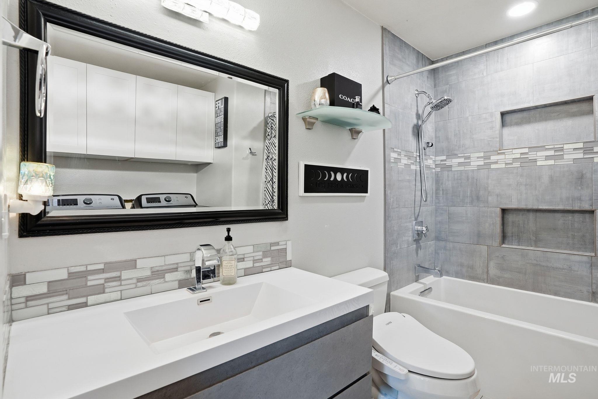 Full bath with vanity, shower / bath combination, and backsplash