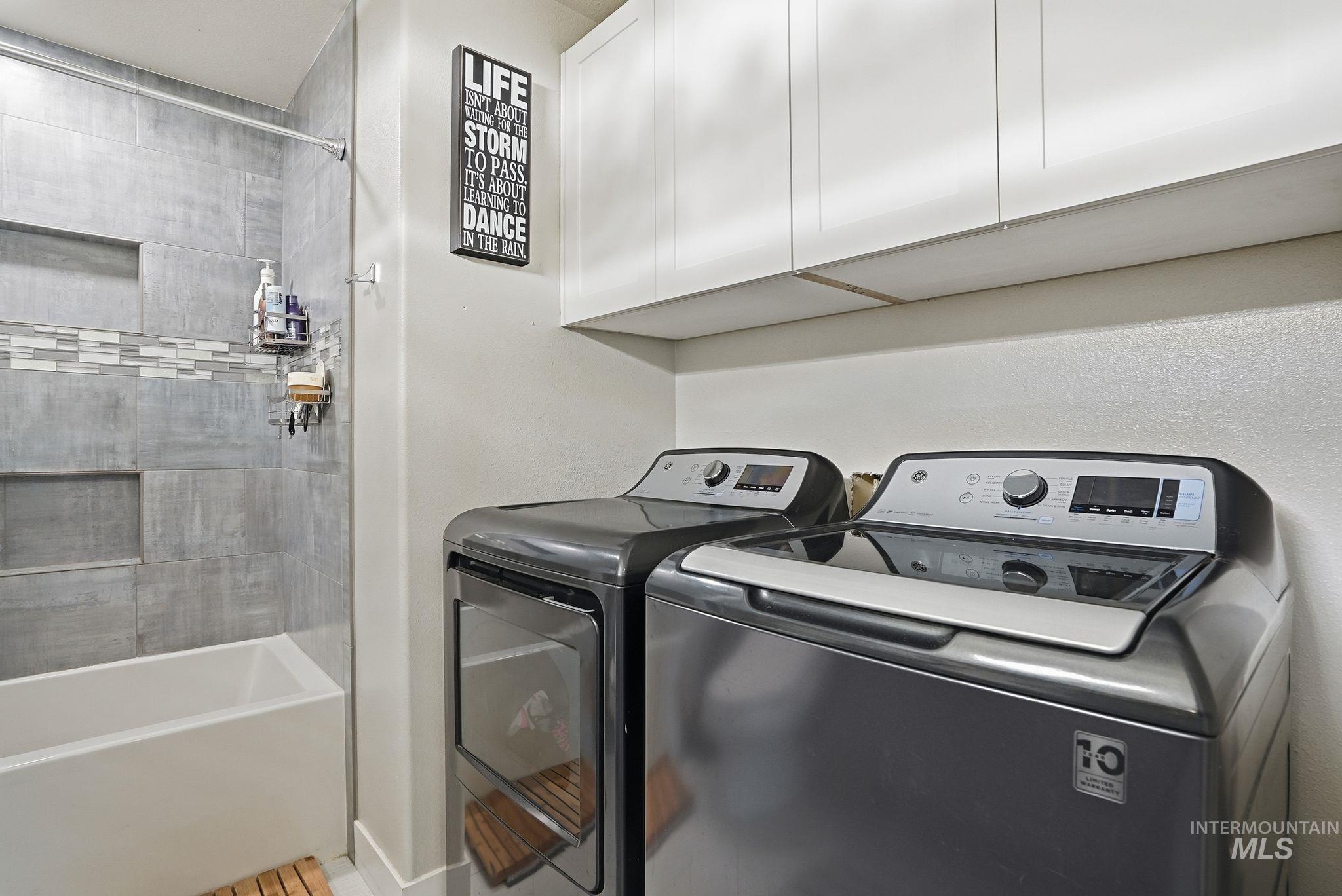 Washroom with washing machine and dryer and baseboards
