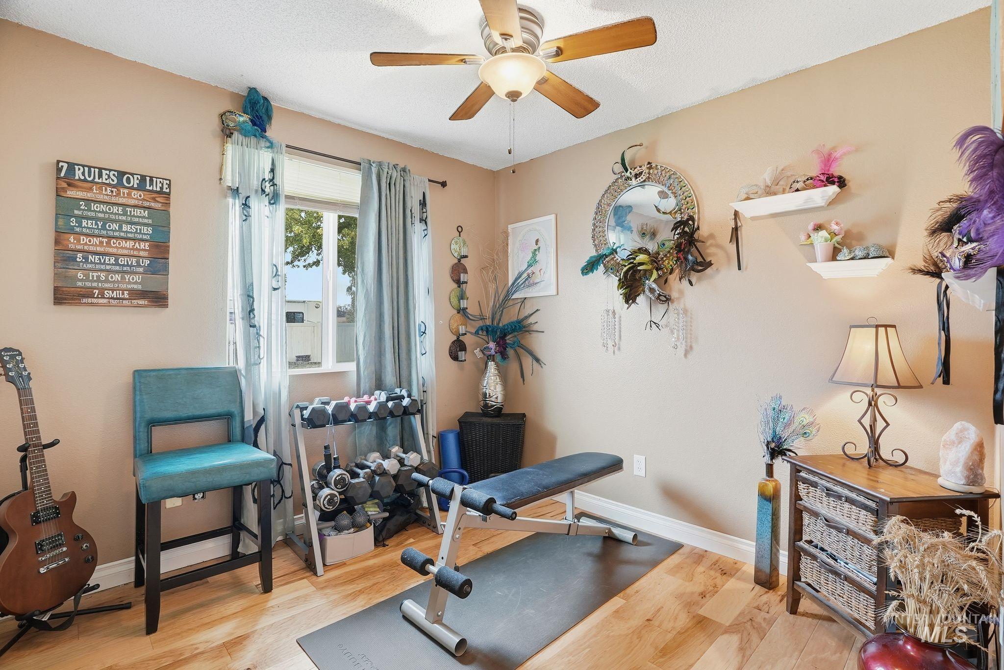Exercise room featuring light wood-type flooring and a ceiling fan