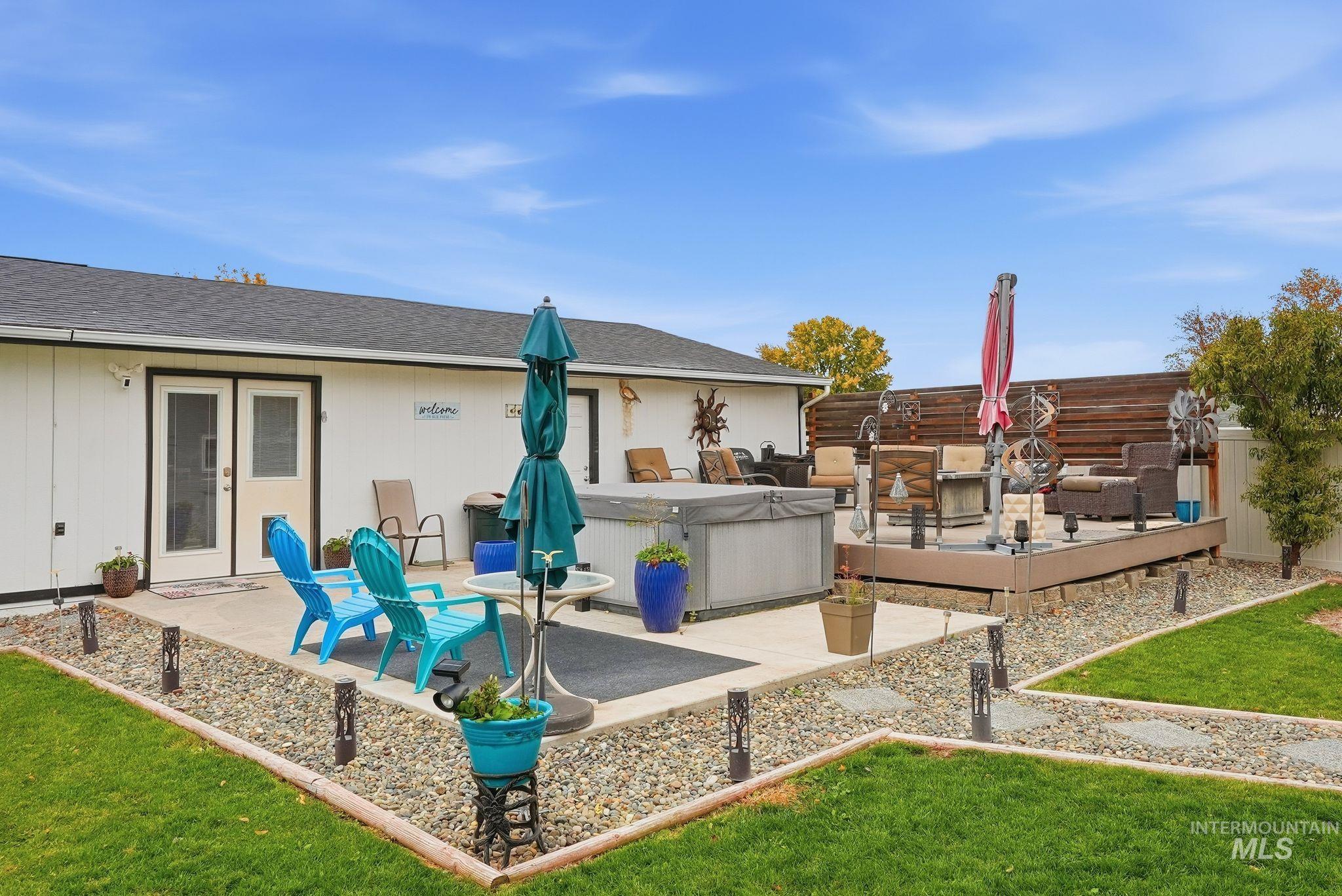 Back of house with a hot tub, a fenced backyard, a shingled roof, and a patio area