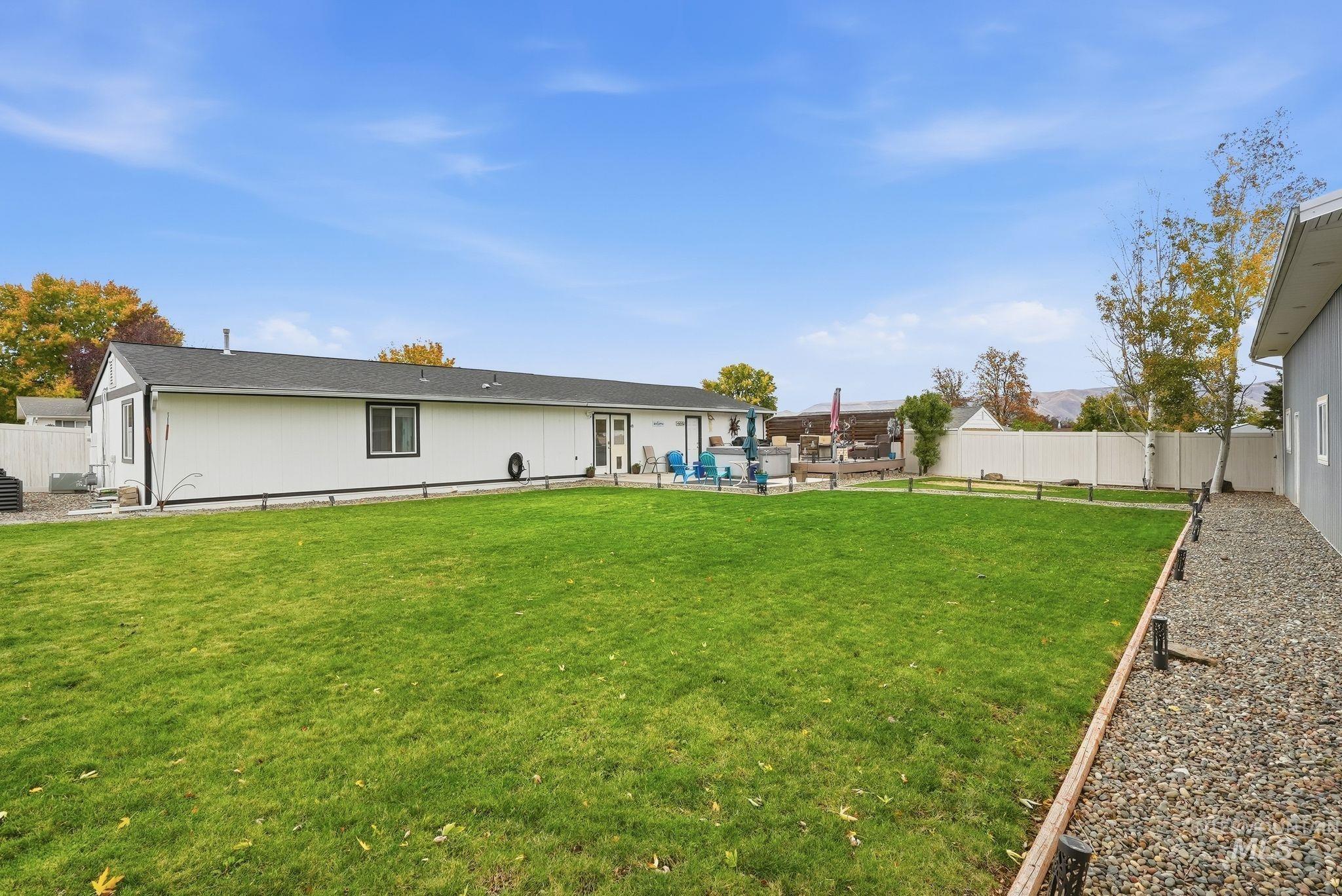 Back of property featuring a fenced backyard, a patio area, roof with shingles, and an outdoor living space