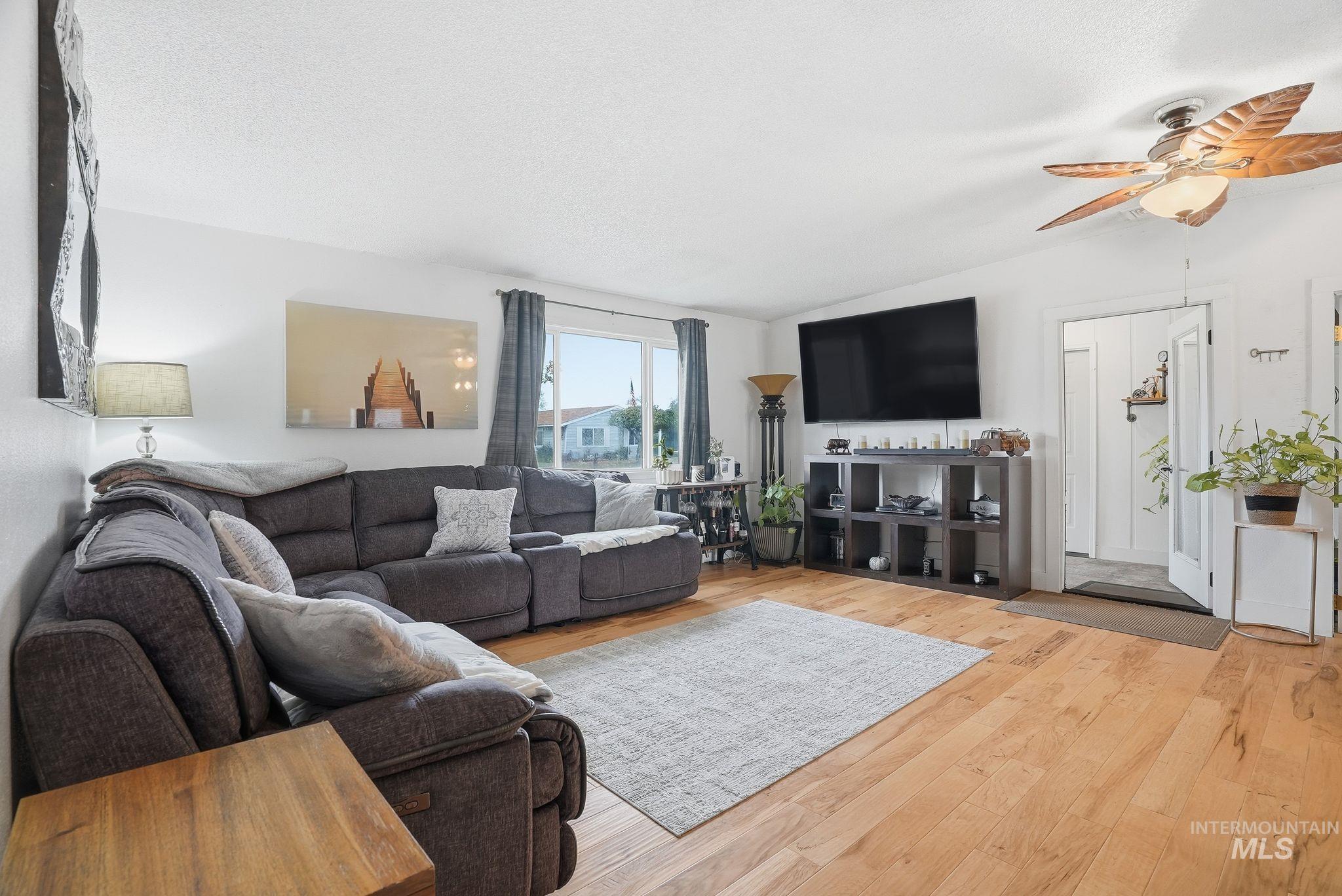 Living room featuring wood finished floors, vaulted ceiling, and a ceiling fan