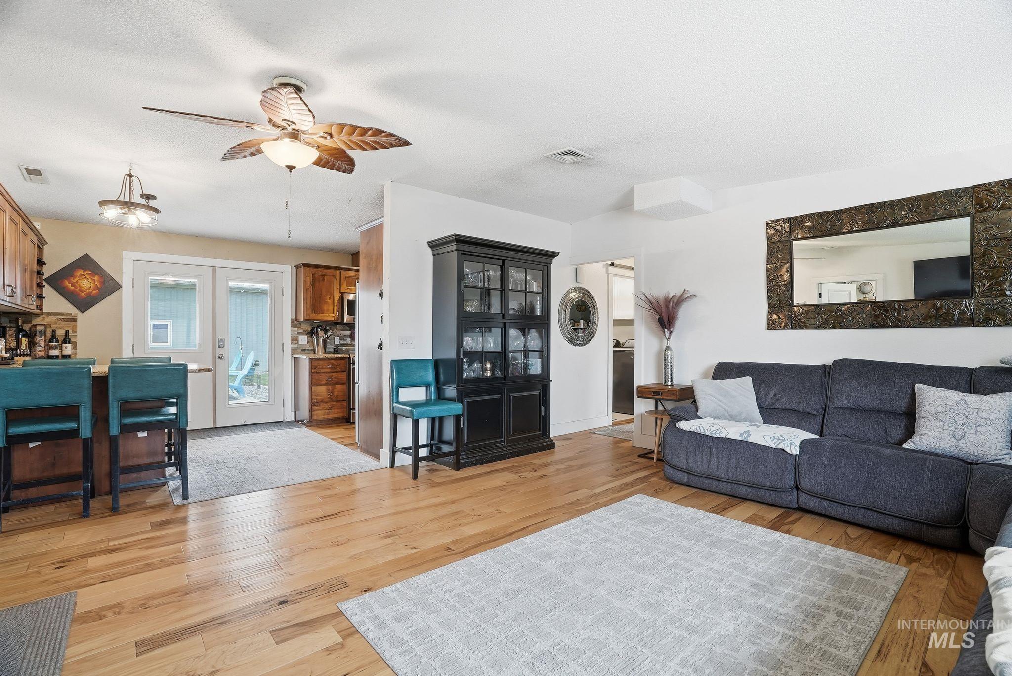 Living area featuring light wood-type flooring, ceiling fan, and a textured ceiling