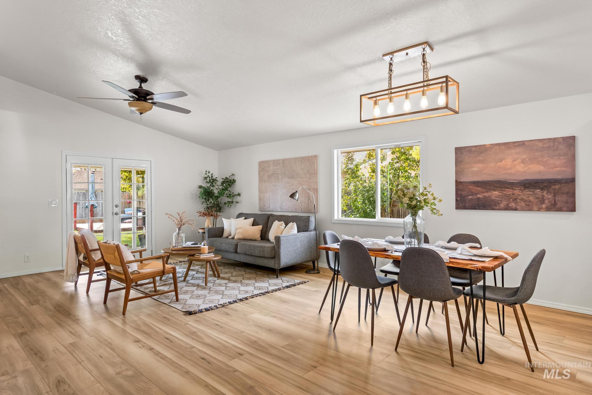 Dining space featuring lofted ceiling, light wood-style floors, french doors, ceiling fan, and a textured ceiling