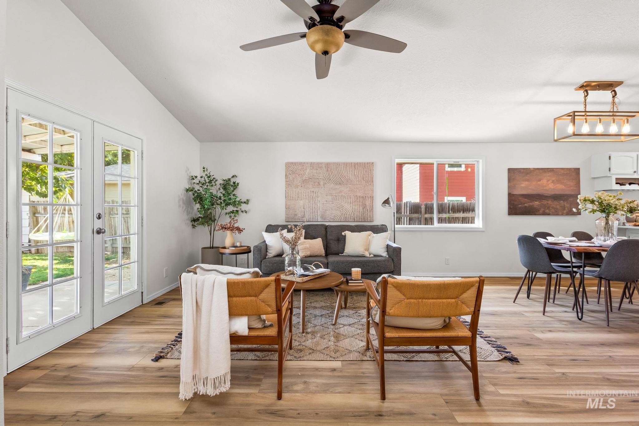 Living area with light wood finished floors, vaulted ceiling, ceiling fan, and french doors