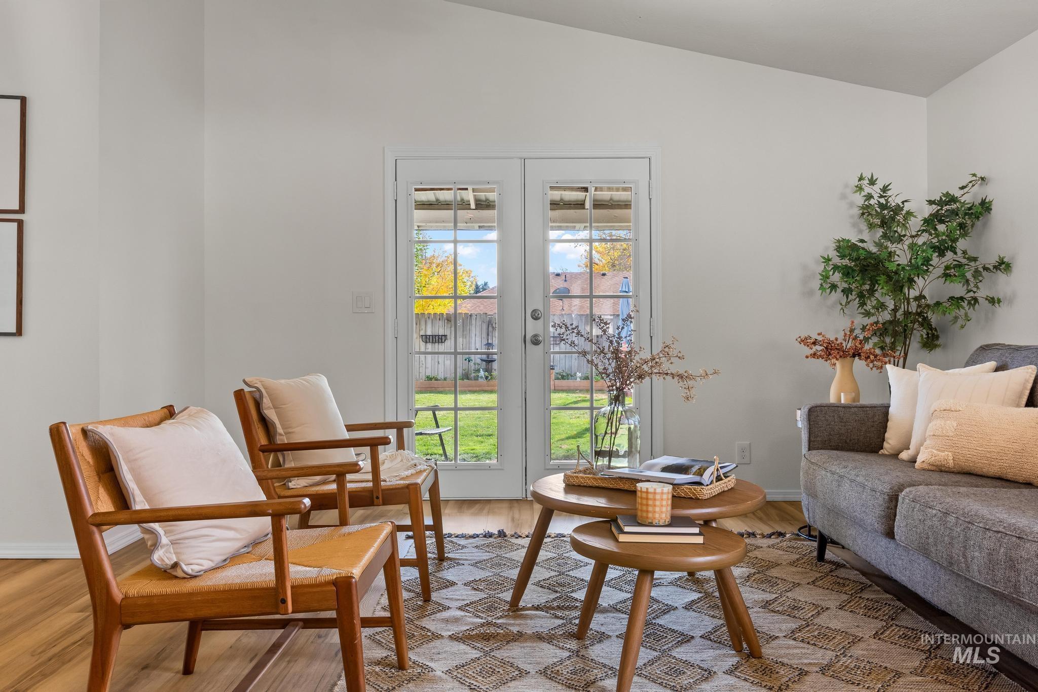 Sitting room featuring light wood-style floors, french doors, and vaulted ceiling