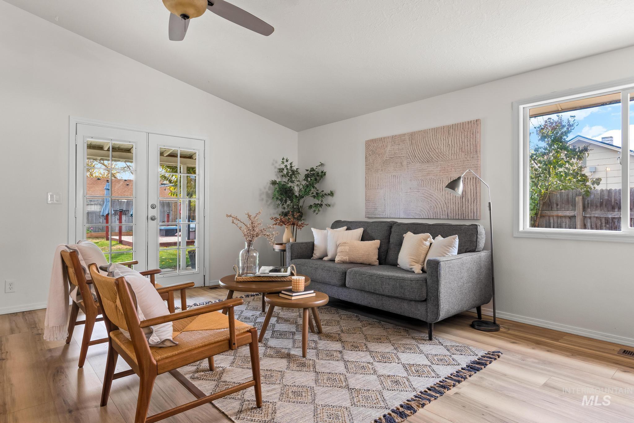Sitting room with lofted ceiling, plenty of natural light, french doors, light wood finished floors, and ceiling fan