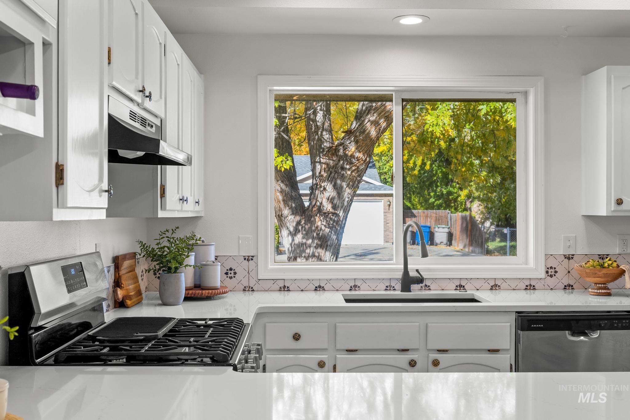 Kitchen with light stone countertops, white cabinetry, and recessed lighting