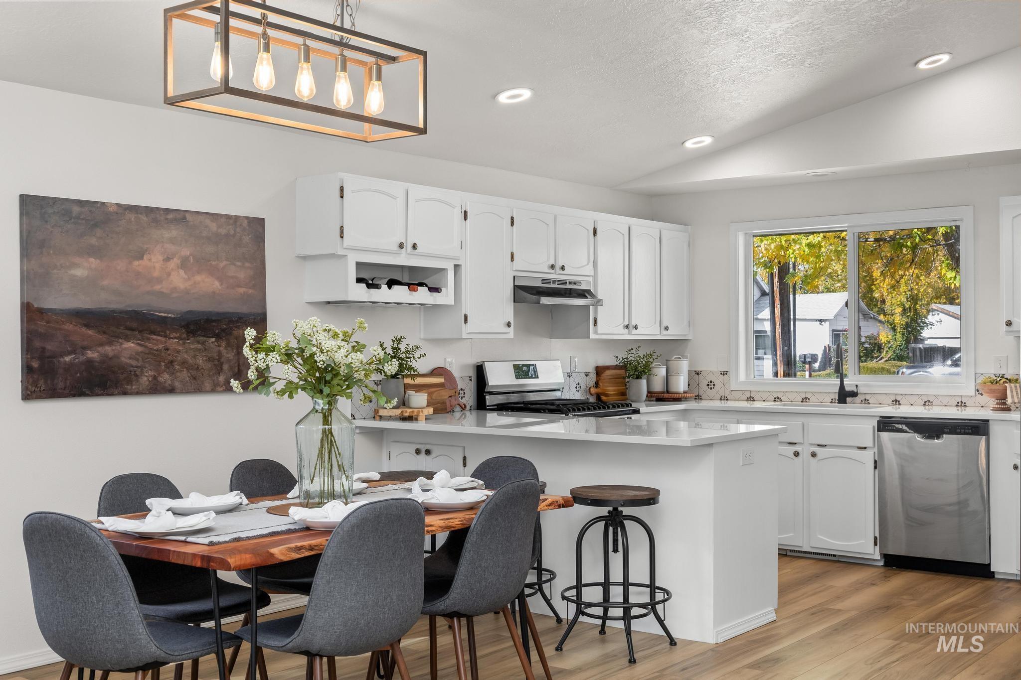 Kitchen with white cabinetry, a peninsula, recessed lighting, appliances with stainless steel finishes, and lofted ceiling