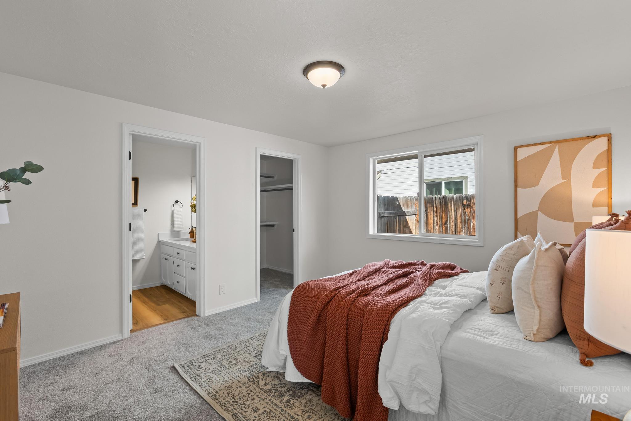 Bedroom featuring a spacious closet, light carpet, and ensuite bathroom