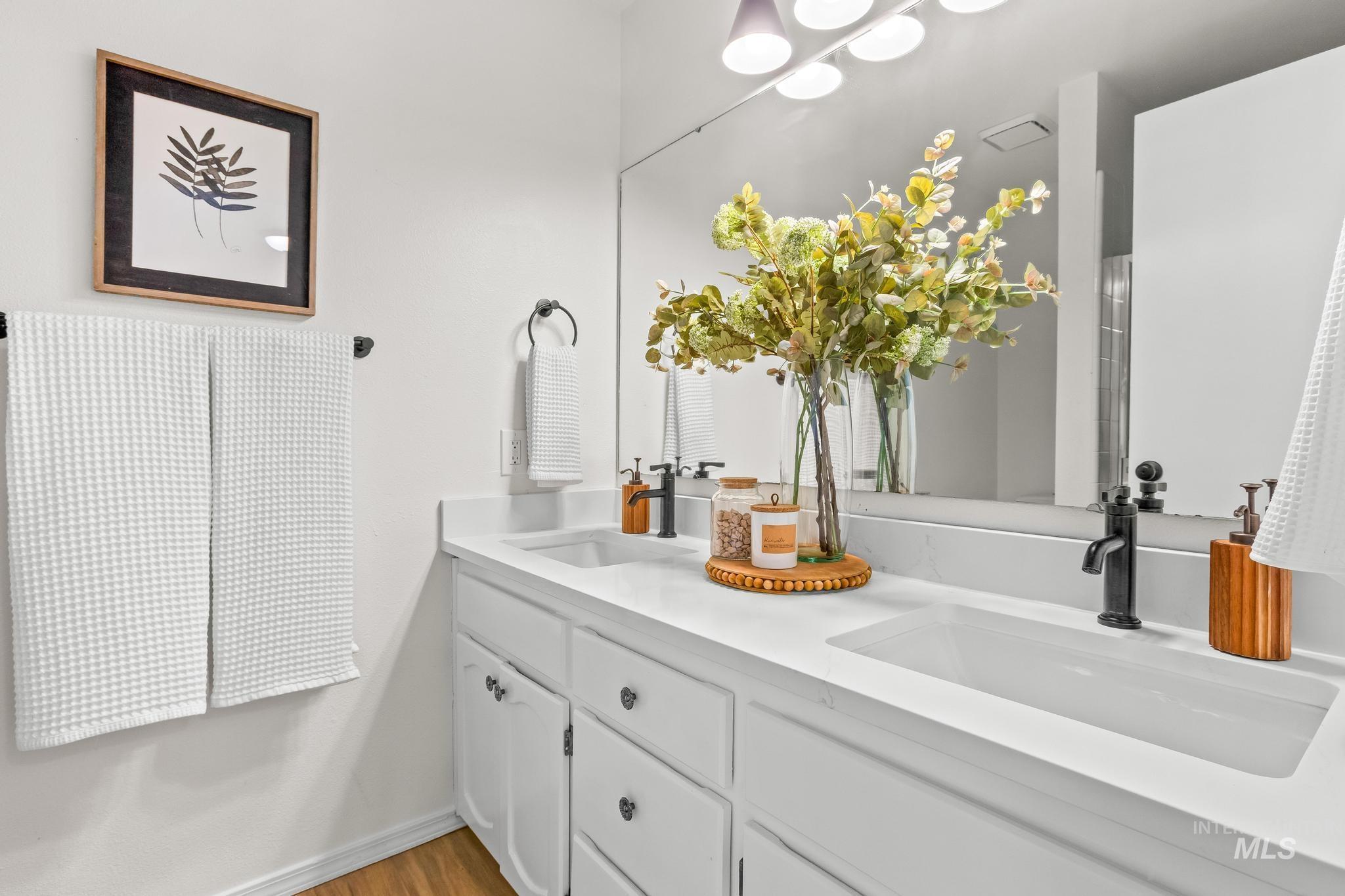 Bathroom with double vanity and light wood finished floors