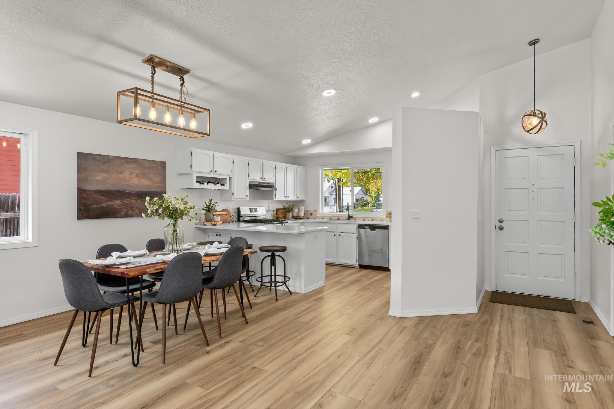Dining area featuring light wood-type flooring, vaulted ceiling, recessed lighting, and a textured ceiling