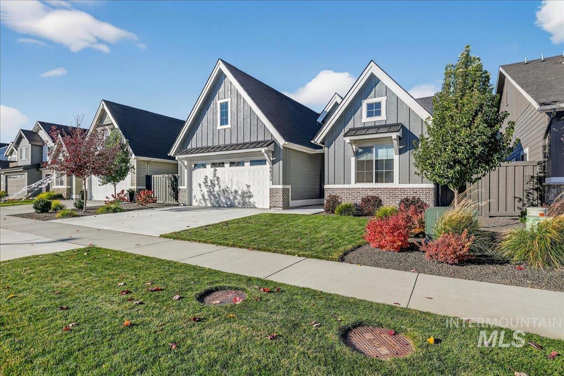 View of front of house featuring a garage, concrete driveway, board and batten siding, a standing seam roof, and brick siding