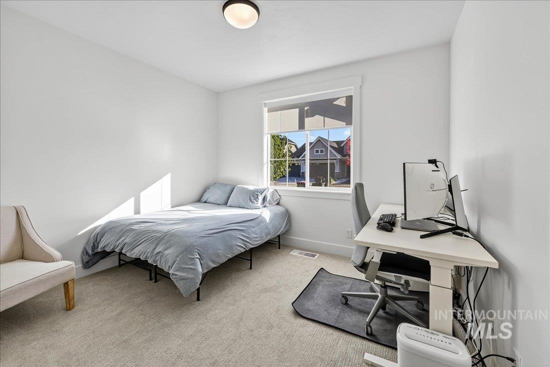 Bedroom featuring light colored carpet and an office area