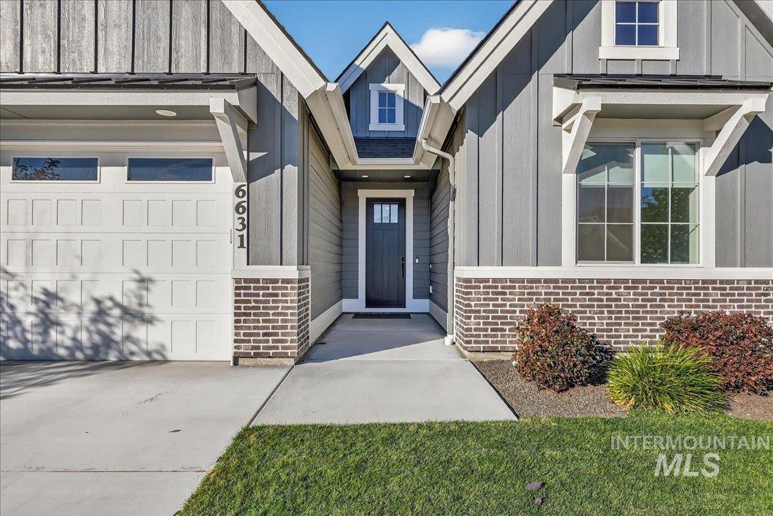 View of exterior entry featuring brick siding, board and batten siding, and concrete driveway