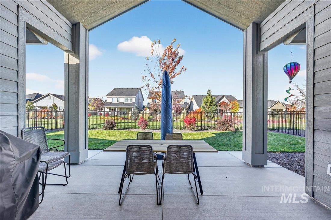 Fenced backyard with a patio area, outdoor dining area, a residential view, and a grill