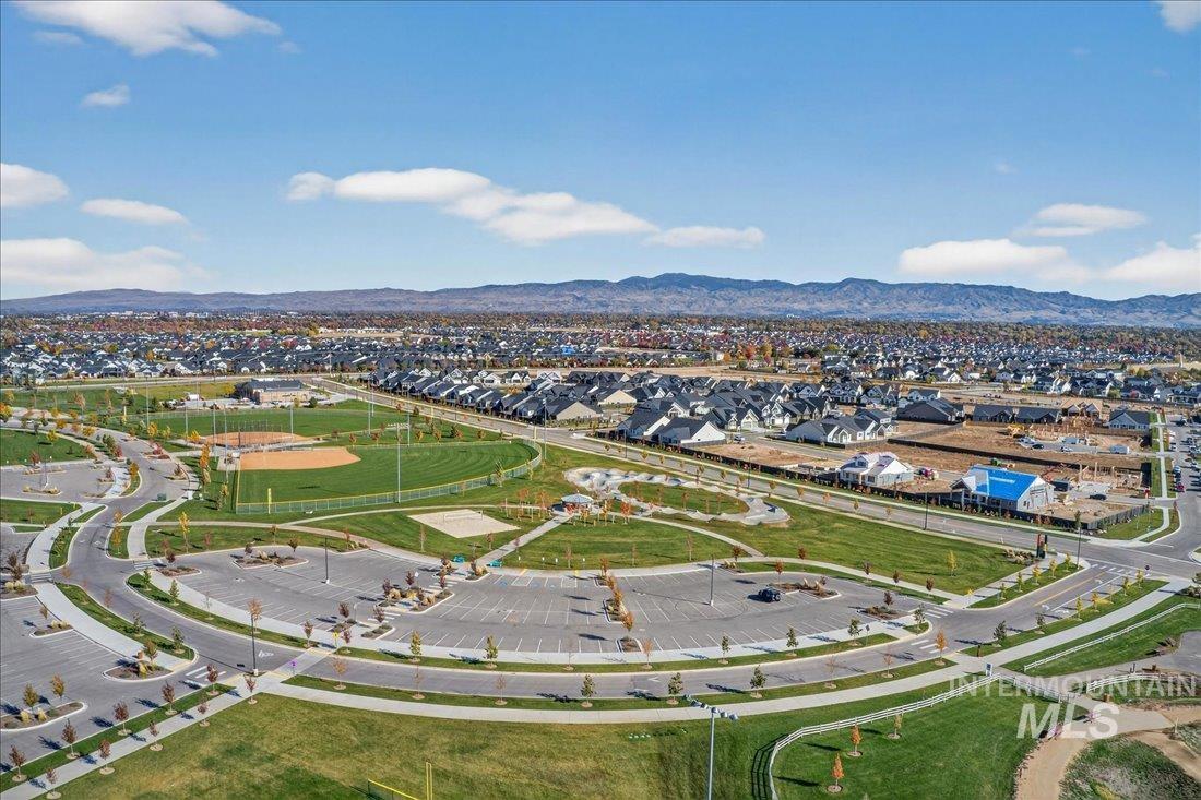 Aerial view of property and surrounding area featuring nearby suburban area and a mountainous background