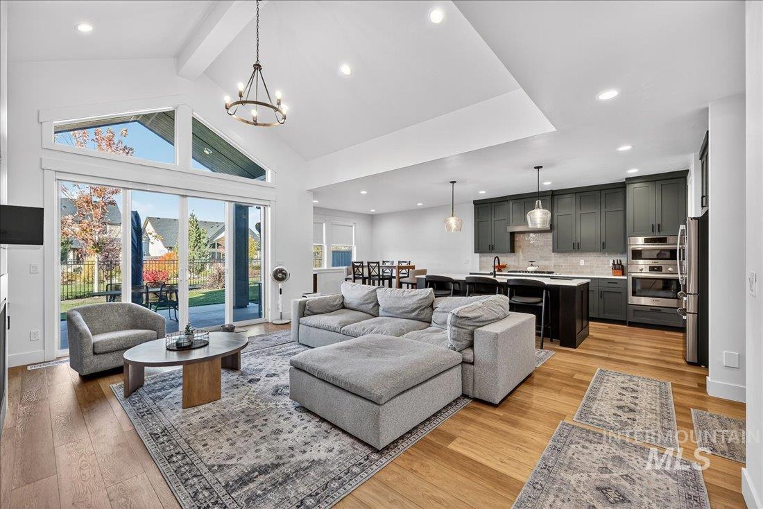 Living area with beam ceiling, light wood-type flooring, high vaulted ceiling, recessed lighting, and a chandelier