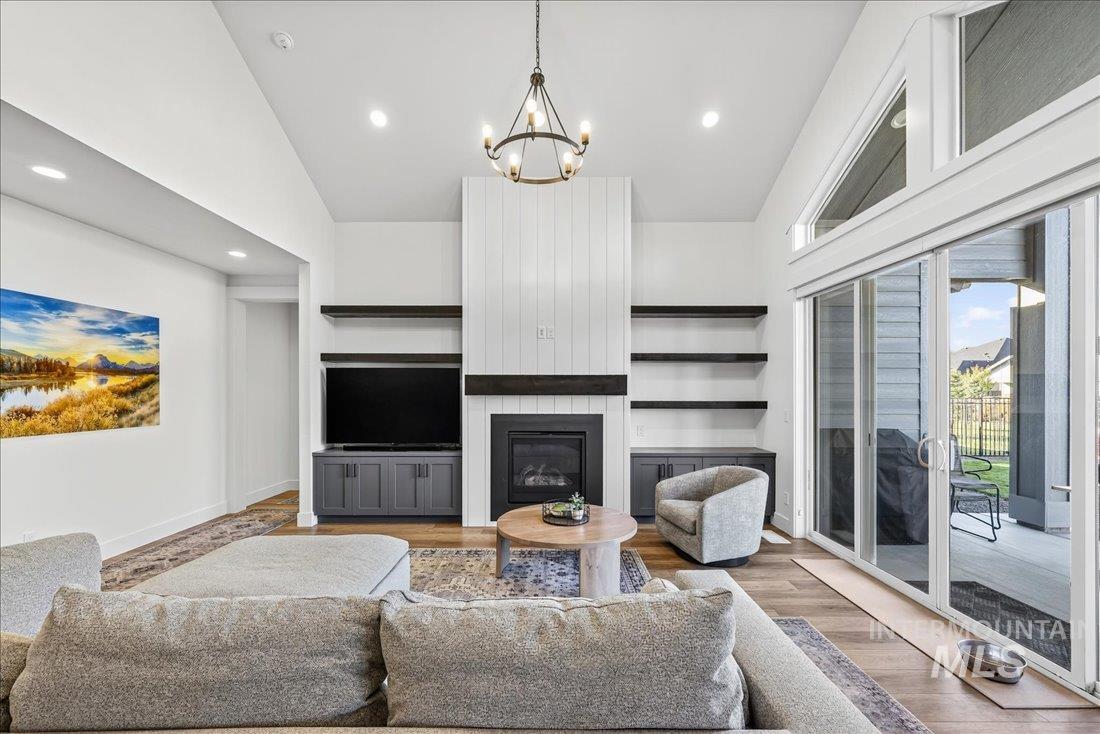 Living area featuring wood finished floors, a fireplace, recessed lighting, a chandelier, and high vaulted ceiling